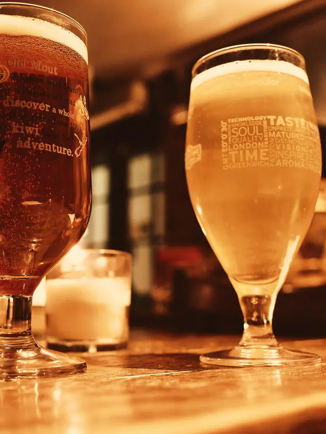 Două halbe de bere pe o masă de lemn, în lumina caldă a serii
