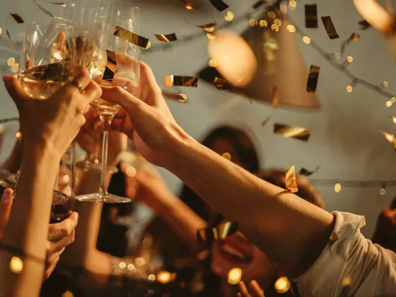 Prieteni care ciocnesc pahare printre confetti aurii