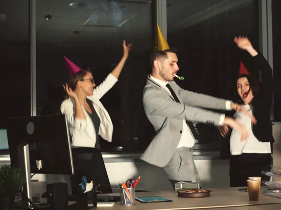 Colegi cu coifuri de petrecere care dansează la o petrecere de birou